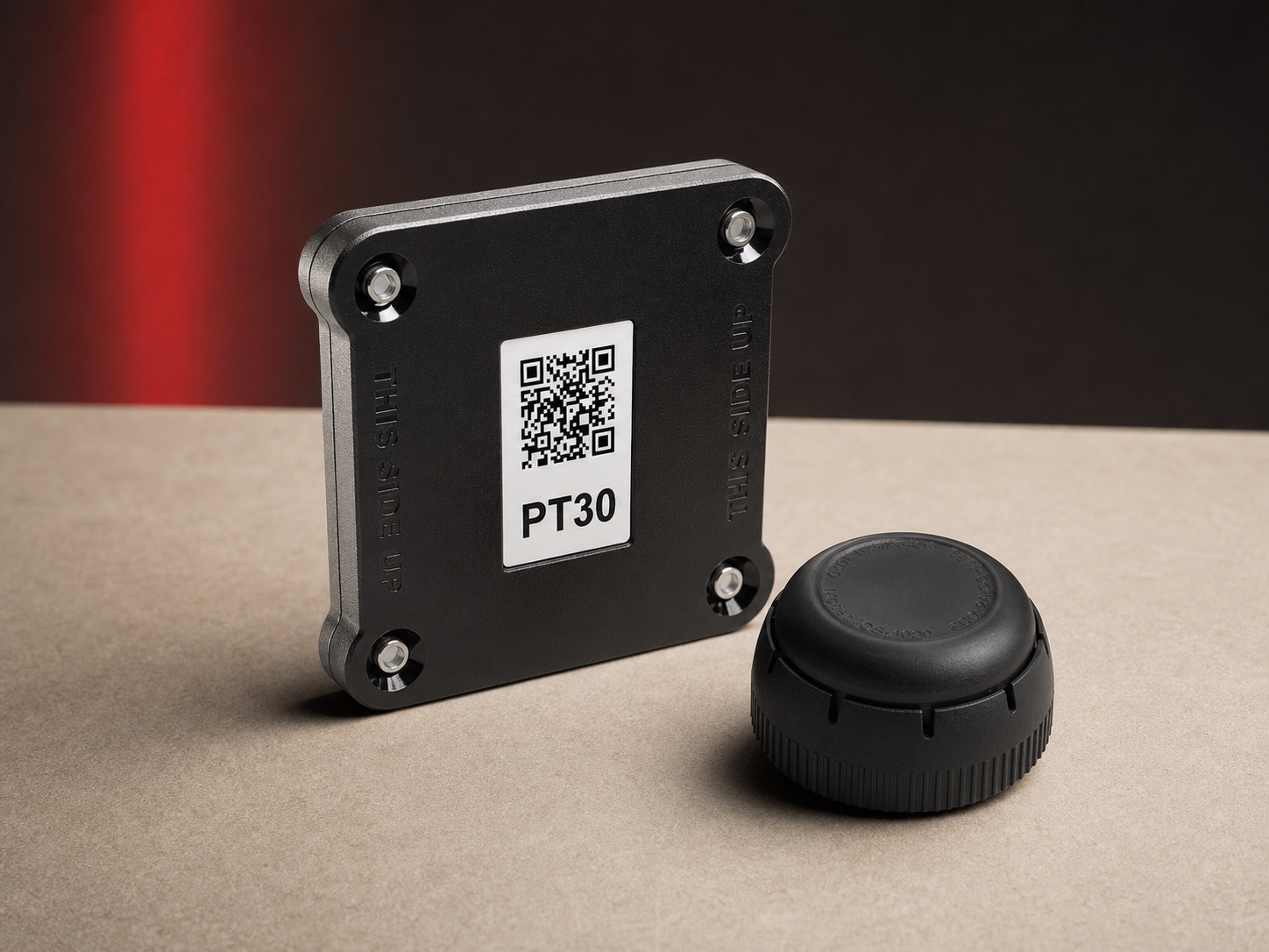 Black electronic logging device module and round connector photographed on a beige studio surface